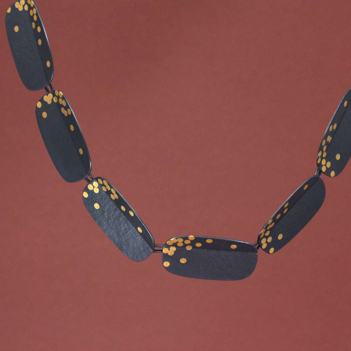 Oxidised silver and keum boo  oblong fold necklace a terracotta background